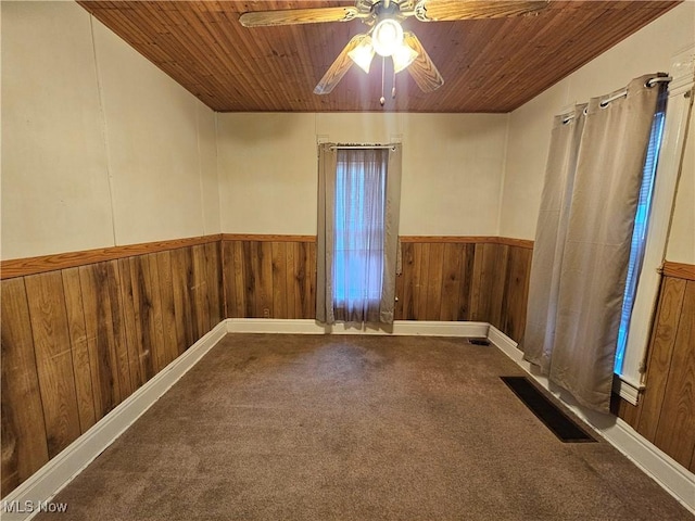 carpeted spare room featuring ceiling fan and wooden ceiling