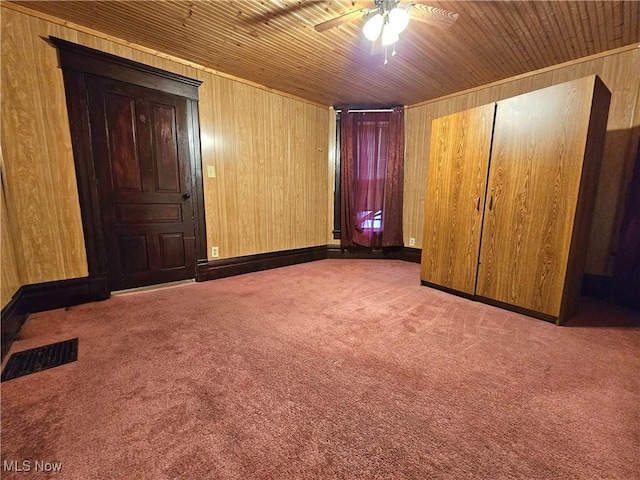 unfurnished bedroom featuring light colored carpet, wood ceiling, ceiling fan, and wood walls