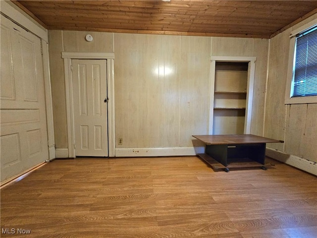 unfurnished bedroom featuring wooden walls, wood ceiling, and light hardwood / wood-style floors