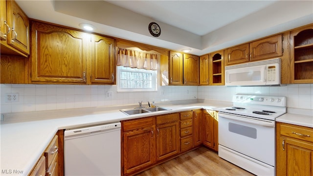 kitchen with tasteful backsplash, white appliances, sink, and light hardwood / wood-style flooring