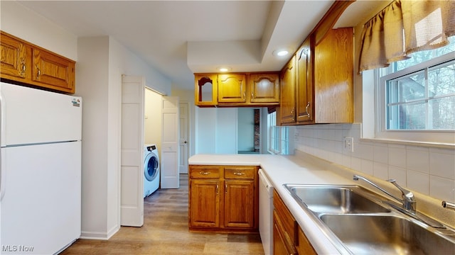 kitchen featuring tasteful backsplash, white appliances, sink, light hardwood / wood-style flooring, and washer / dryer