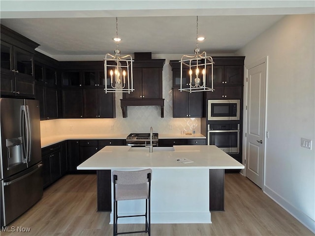 kitchen with a center island with sink, an inviting chandelier, pendant lighting, and appliances with stainless steel finishes