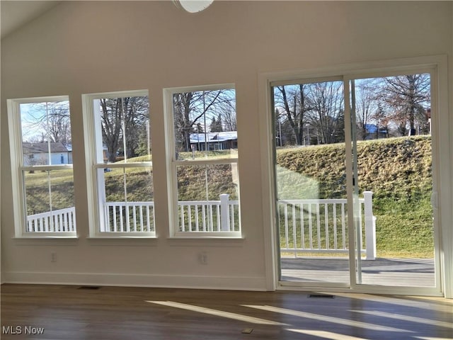 doorway with hardwood / wood-style floors and vaulted ceiling