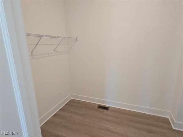 walk in closet with dark wood-type flooring