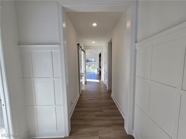 hall with a barn door and dark wood-type flooring