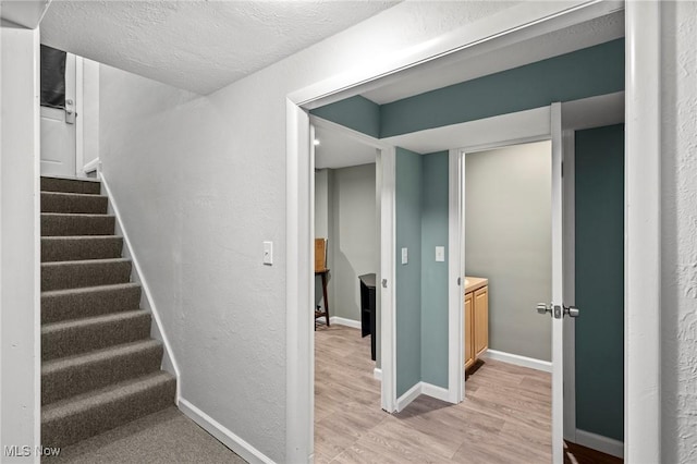 stairs with wood-type flooring and a textured ceiling