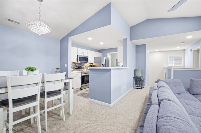 kitchen with kitchen peninsula, appliances with stainless steel finishes, backsplash, decorative light fixtures, and white cabinets