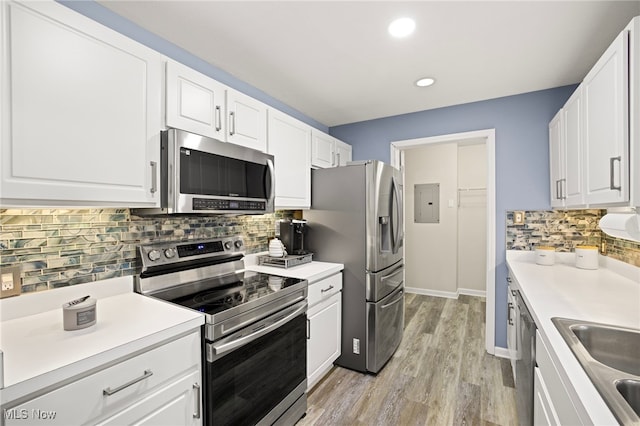 kitchen featuring backsplash, white cabinetry, light wood-type flooring, and appliances with stainless steel finishes