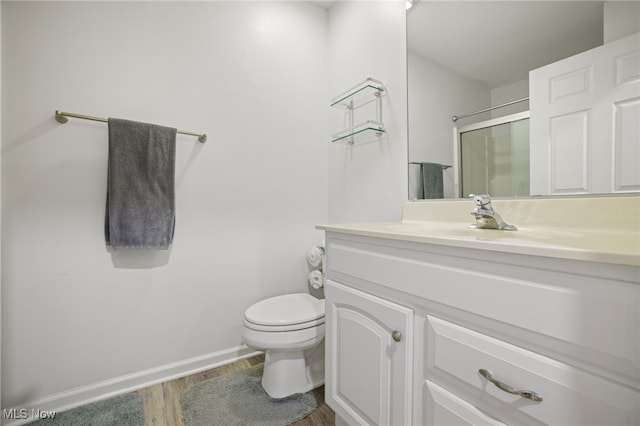 bathroom featuring vanity, toilet, a shower with shower door, and wood-type flooring