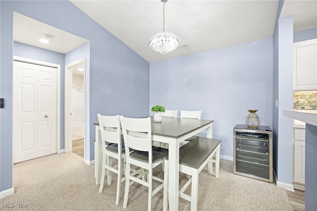 carpeted dining space featuring a chandelier, beverage cooler, and lofted ceiling