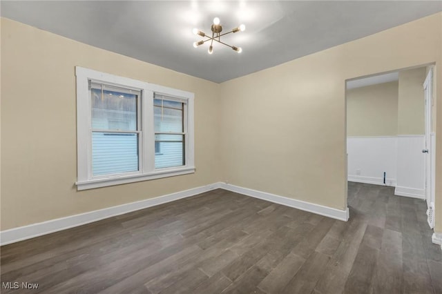 empty room with dark hardwood / wood-style floors and a notable chandelier