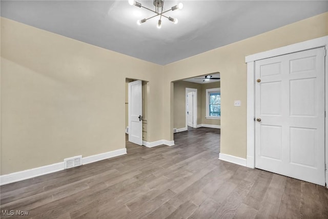 unfurnished room featuring wood-type flooring and ceiling fan with notable chandelier