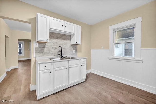 kitchen with white cabinets, light wood-type flooring, and sink