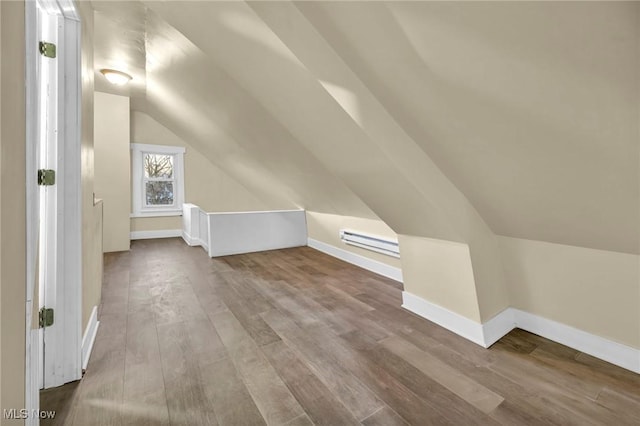 additional living space featuring wood-type flooring, lofted ceiling, and a baseboard radiator