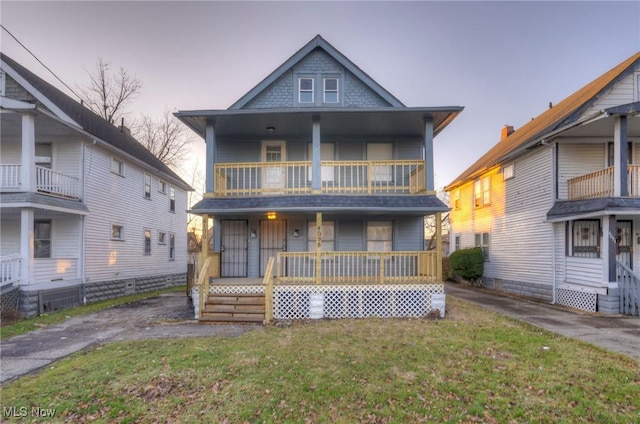 view of front facade with covered porch, a balcony, and a lawn