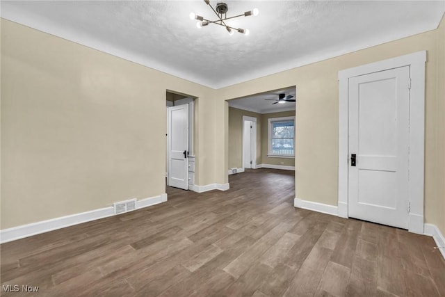 unfurnished room with hardwood / wood-style floors, ceiling fan with notable chandelier, and a textured ceiling