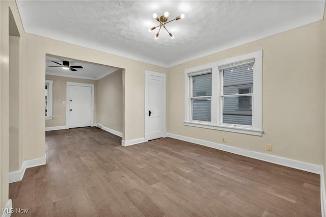 spare room with hardwood / wood-style floors, ceiling fan with notable chandelier, and a textured ceiling