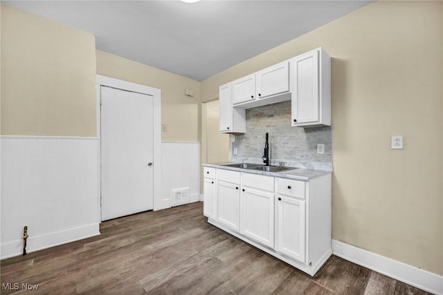 kitchen featuring white cabinets, hardwood / wood-style floors, backsplash, and sink