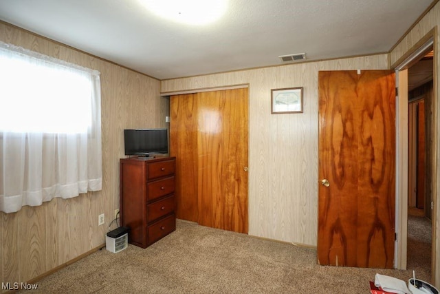 carpeted bedroom with wooden walls and a closet