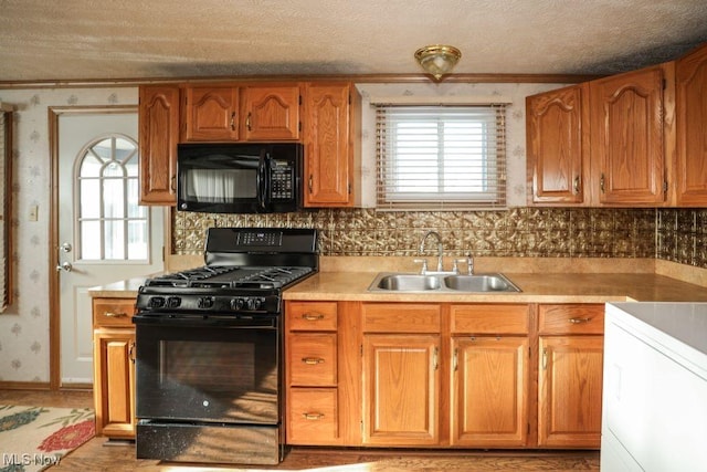 kitchen featuring sink, black appliances, a textured ceiling, and ornamental molding