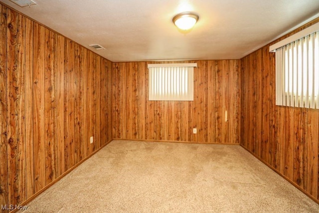 carpeted empty room featuring wood walls