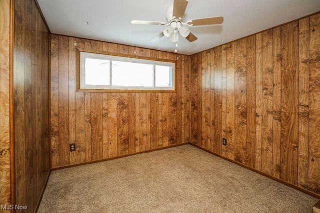 empty room featuring light carpet, ceiling fan, and wooden walls