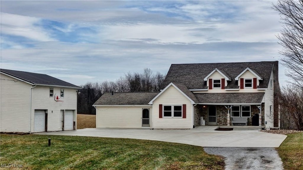 cape cod-style house featuring a garage, covered porch, and a front lawn