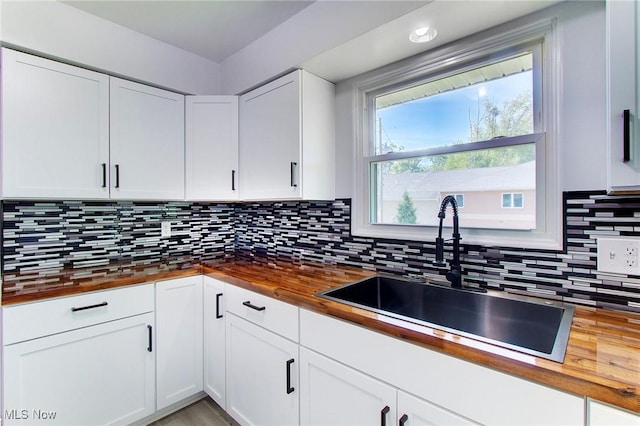 kitchen featuring white cabinets, butcher block counters, sink, and tasteful backsplash