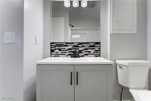 bathroom with vanity, a shower, backsplash, and toilet