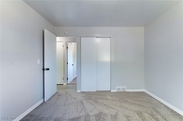 unfurnished bedroom with light carpet and a closet