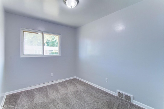 carpeted empty room featuring a baseboard heating unit