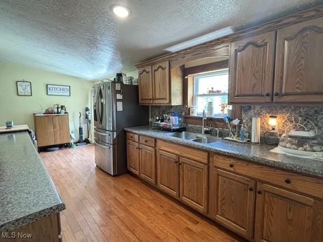 kitchen featuring decorative backsplash, a textured ceiling, light hardwood / wood-style floors, and sink