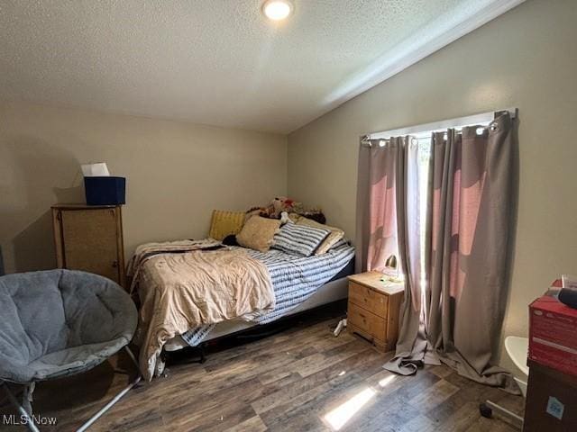 bedroom featuring hardwood / wood-style floors, a textured ceiling, and vaulted ceiling