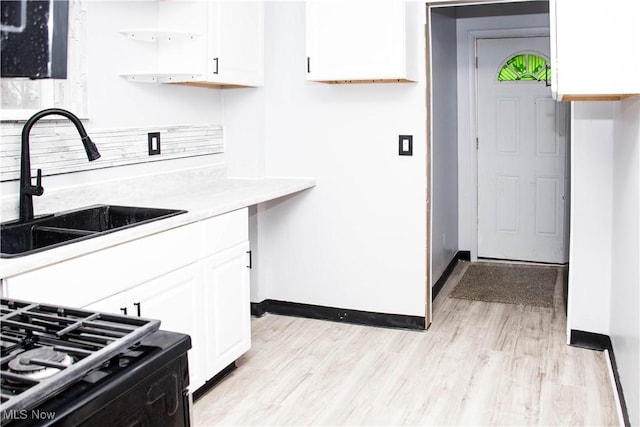 kitchen with white cabinetry, sink, and light wood-type flooring