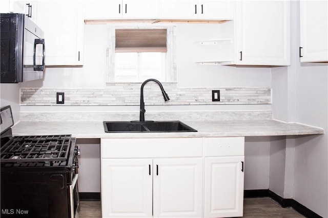 kitchen with white cabinets, gas stove, dark wood-type flooring, and sink