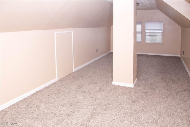 bonus room with lofted ceiling and light carpet