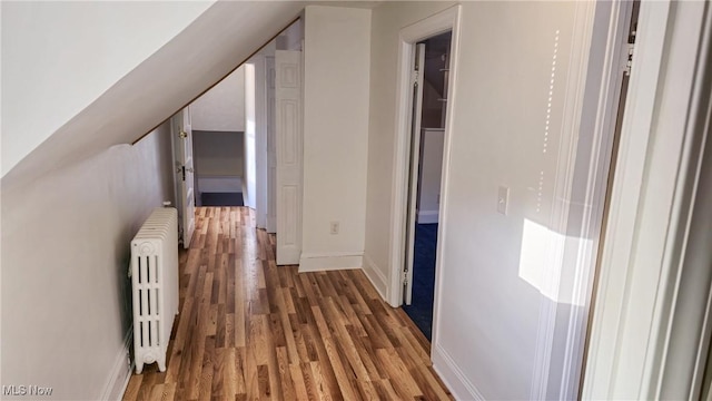 corridor with dark hardwood / wood-style flooring, radiator heating unit, and lofted ceiling