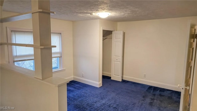 unfurnished bedroom with a closet, dark carpet, and a textured ceiling