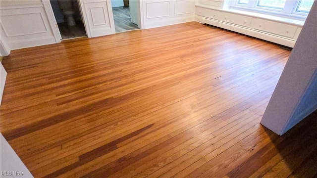 unfurnished bedroom with light wood-type flooring and a baseboard heating unit