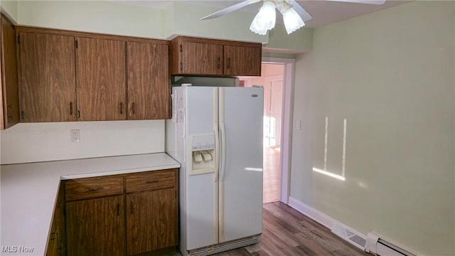 kitchen featuring white refrigerator with ice dispenser, dark hardwood / wood-style flooring, ceiling fan, and a baseboard heating unit