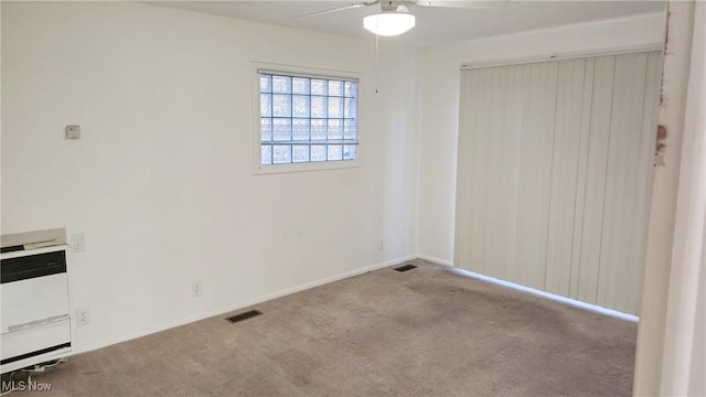 carpeted empty room with heating unit and ceiling fan