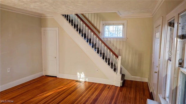 stairway with hardwood / wood-style flooring and crown molding