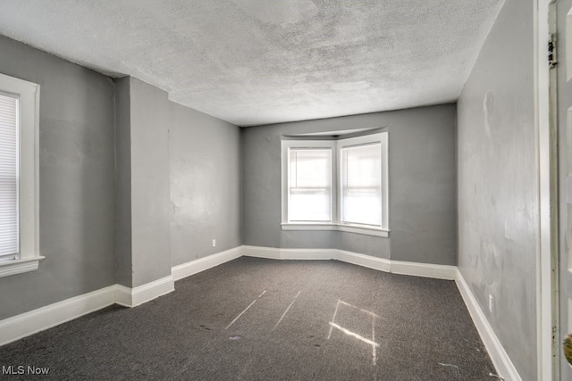 carpeted empty room with a textured ceiling