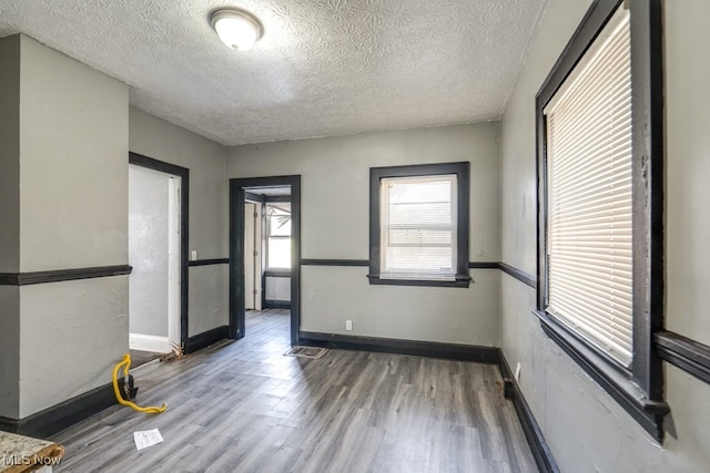 unfurnished room featuring dark hardwood / wood-style flooring and a textured ceiling