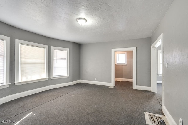 carpeted empty room featuring a textured ceiling