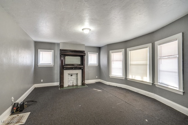 unfurnished living room with carpet flooring, a healthy amount of sunlight, and a textured ceiling