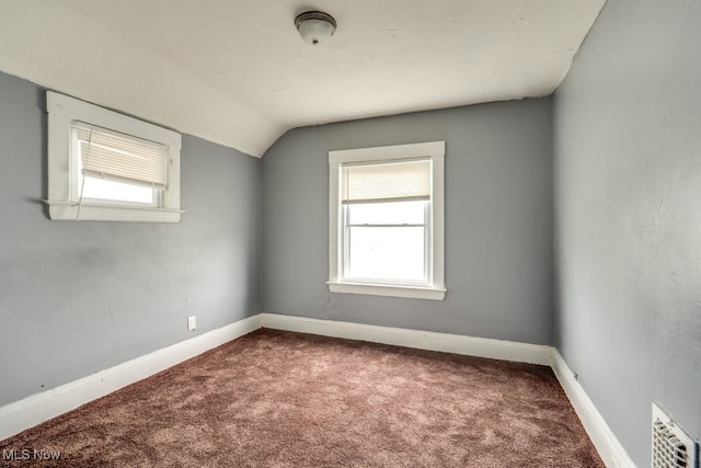 carpeted spare room featuring vaulted ceiling