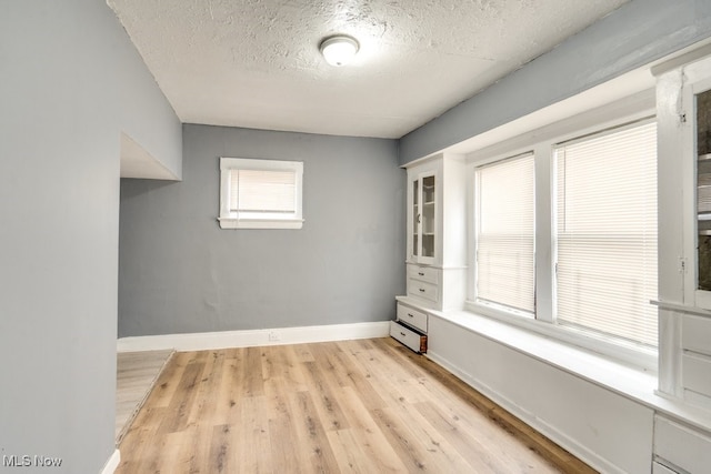 empty room featuring a textured ceiling and light hardwood / wood-style floors