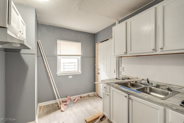 kitchen with decorative backsplash, sink, white cabinets, and light hardwood / wood-style flooring