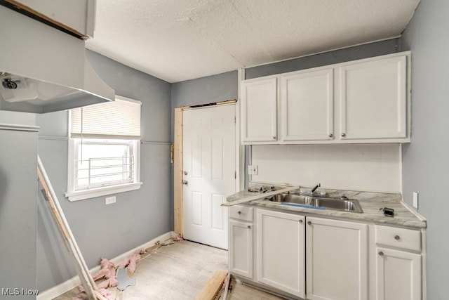 kitchen featuring white cabinets, sink, and a textured ceiling